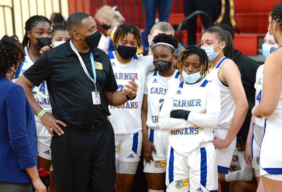 Garner Trojans head coach William Stigler, left, speaks to his team following their 74-38 loss to the Vance Cougars in the 4A State Championship at Wheatmore High School in Trinity, NC on Saturday, March 6, 2021.