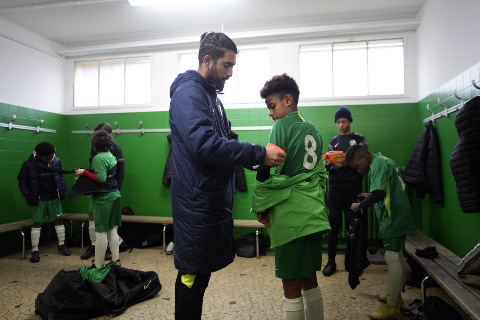 Coach of the club where Kylian Mbappe played as a kid, Sari Rohat, places the captain armband prior to a match on the Leo Lagrange stadium in Bondy, east of Paris, Saturday, Dec. 17, 2022. On the football fields where Kylian Mbappe hones the feints, dribbles and shots that all of France hopes to see in Sunday's World Cup final against Argentine, the next generation of French kids with big dreams is already hard at work to follow in the superstar's footsteps. (AP Photo/Thibault Camus)