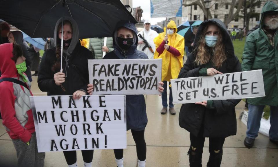 Protesters hold signs during a rally against Michigan’s stay-at-home order in Lansing, Michigan, on 14 May.