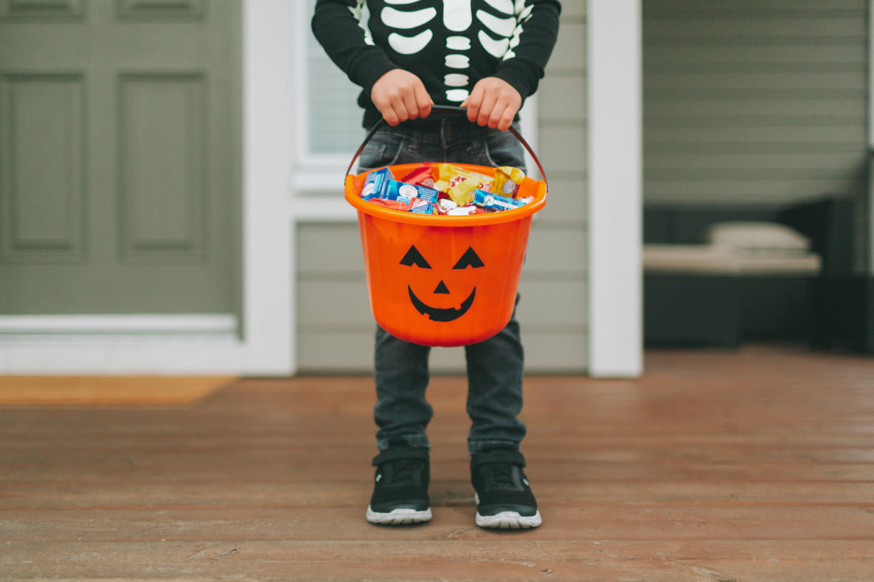 little boy on halloween holding orange halloween candy bucket
