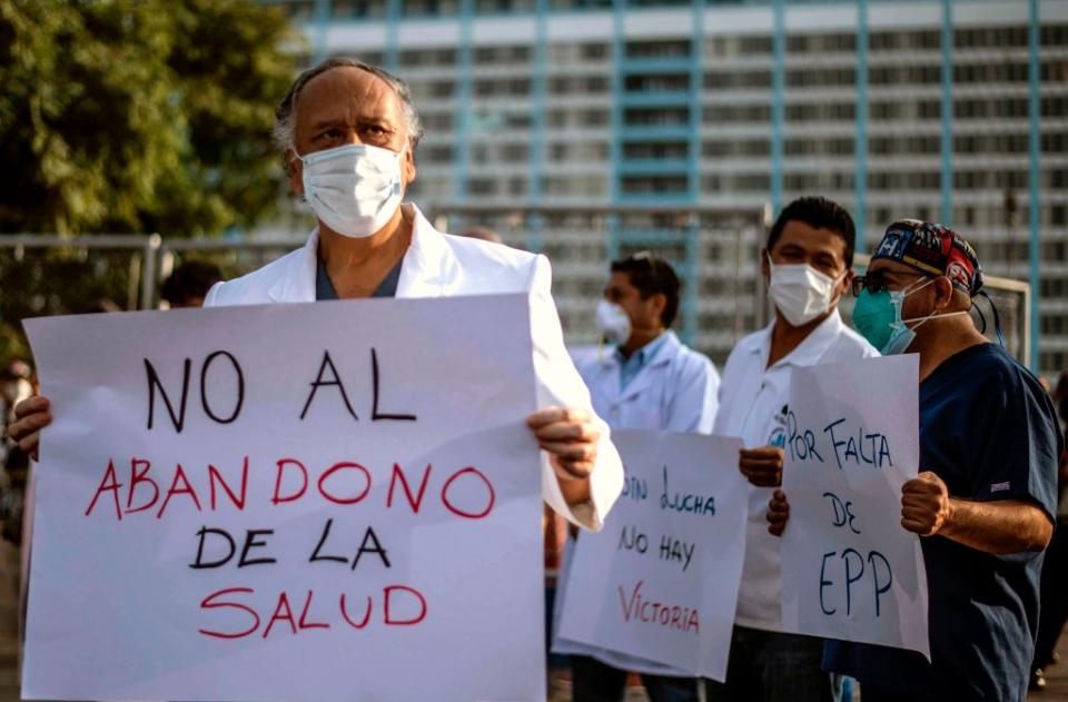 Health workers protest for the lack of security equipment demanding the resignation of Peruvian Health Minister Victor Zamora with a sign reading No to the abandonment of healthcare outside the Edgardo Rebagliati public hospital in Lima on May 13, 2020. | Ernesto Benavides – AFP/Getty Images