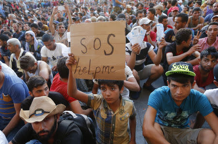 A child holds a self-made placard reading "SOS help me" outside the railways station in Budapest, Hungary September 2, 2015. REUTERS/Laszlo Balogh