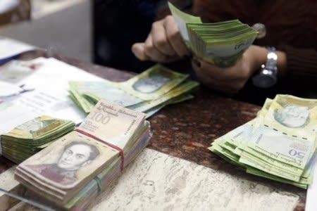 FILE PHOTO - A cashier counts bolivars at money exchange in Caracas, Febreuary 24, 2015. REUTERS/Carlos Garcia Rawlins