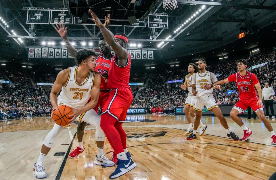 PC's Clifton Moore, left, fends off Esahia Nyiwe and Dylan Addae-Wusu of St. John's in the final minutes of their Jan. 9 game at Amica Mutual Pavilion. The Friars won, 83-80.