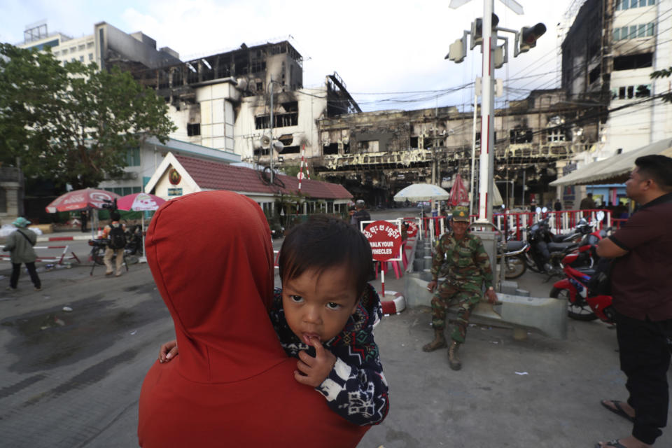 Residents watch a ruined building at the scene of a massive fire at a Cambodian hotel casino in Poipet, west of Phnom Penh, Cambodia, Friday, Dec. 30, 2022. The fire at the Grand Diamond City casino and hotel Thursday injured over 60 people and killed more than a dozen, a number that officials warned would rise after the search for bodies resumes Friday. (AP Photo/Heng Sinith)