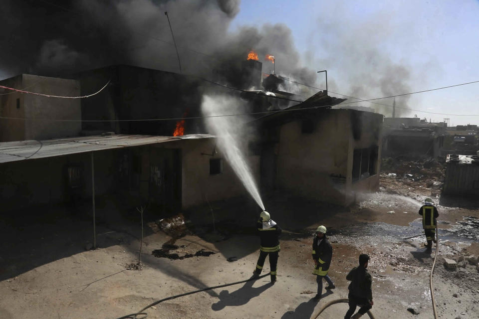 This photo released Tuesday, Feb. 19, 2019, by the Syrian Civil Defense group known as the White Helmets, shows Syrian White Helmet civil defense workers extinguishing a fire at a bakery after being hit by a shell from Syrian forces, in the town of Khan Sheikhoun, Idlib, north Syria. The Britain-based Syrian Observatory for Human Rights said the shelling on the town of Khan Sheikhoun hit the main bakery that supplies the town and nearby villages with bread. It said several people were killed in the shelling including children. (Syrian Civil Defense White Helmets via AP)