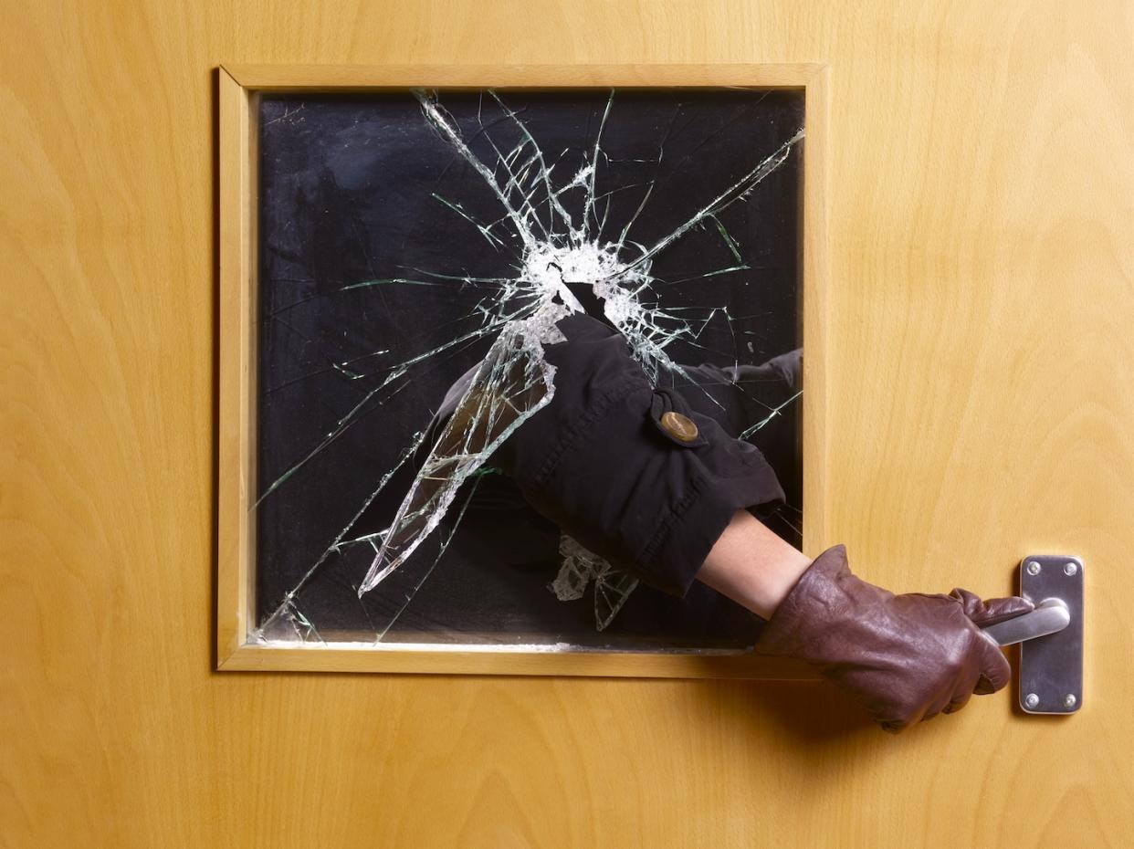 Photo of person entering an office by breaking glass panel of door (Photo: Getty Images)