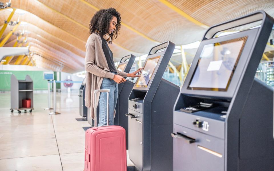 Η γυναίκα χρησιμοποιεί το μηχάνημα check-in στο αεροδρόμιο και παίρνει την κάρτα επιβίβασης