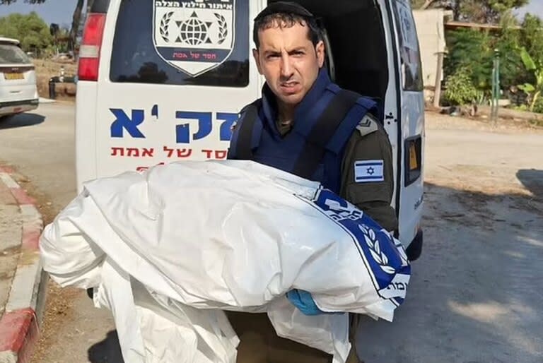 Un rescatista israelí lleva lo que parece ser un cuerpo pequeño, posiblemente un niño, envuelto en una manta