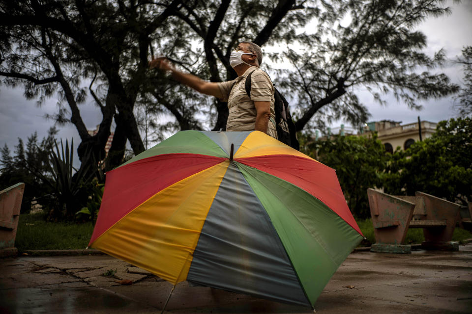 Un hombre mira al tenor cubano Andrés Sánchez Joglar serenar a sus vecinos desde el balcón de su apartamento en La Habana, el domingo 31 de mayo de 2020. El cantante de ópera está dando conciertos desde su casa todos los domingos por la tarde para animar a sus compatriotas en cuarentena durante la pandemia del coronavirus. (AP Foto/Ramón Espinosa)