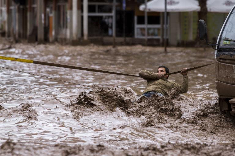 A man clings to a security line to cross a street flooded by the overflowing Copiapo River in Copiapo, Chile on March 26, 2015