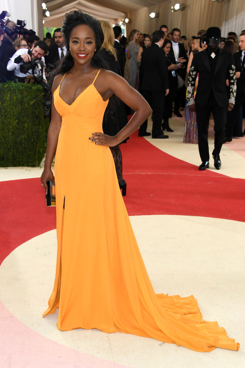 Aja Naomi King in a bright orange gown 