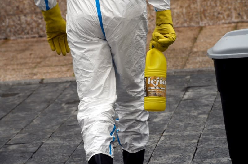 FILE PHOTO: FILE PHOTO: A sanitary worker carries bleach to the nursing home where a woman died and several residents and care providers have been diagnosed with coronavirus disease (COVID-19) in Grado