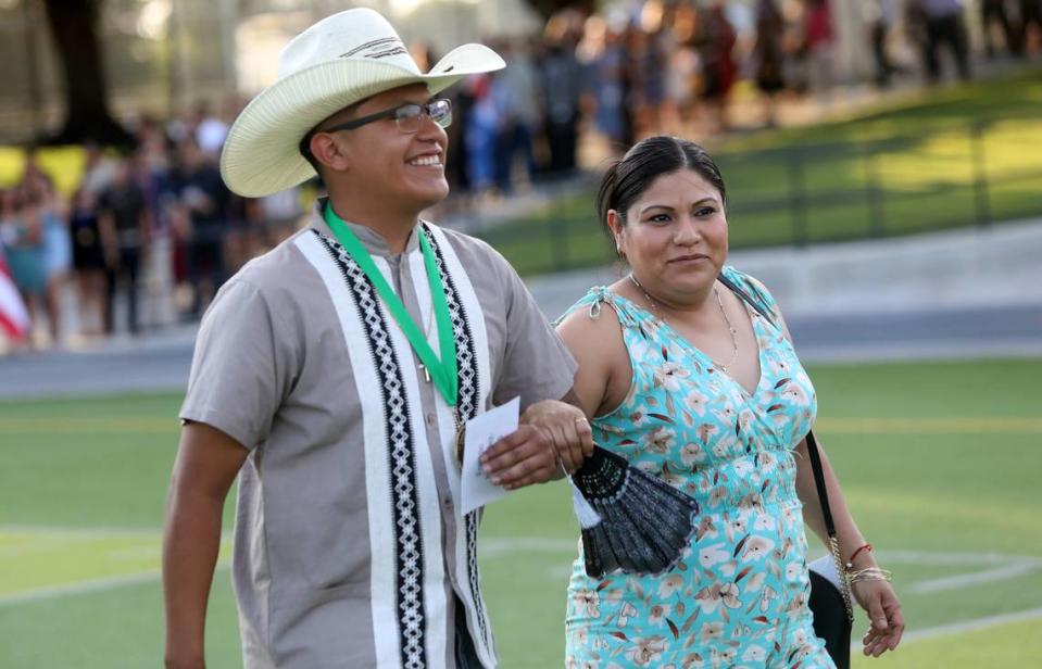 Edison High graduate Edison Hernández Arrellano is accompanied by his mother, María Arrellano, at the start of the inaugural Latinx High School Recognition Celebration at McLane High Stadium on June 4, 2023.