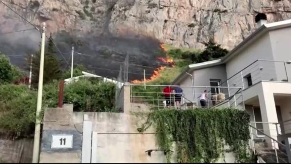 Residents watch from a balcony as wildfires approach homes in Palermo. (Reuters)