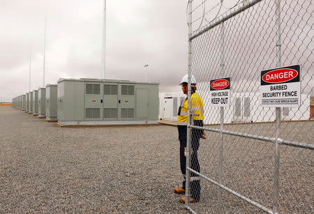 FILE PHOTO: A worker stands at the main gate for the compound housing the Hornsdale Power Reserve, featuring the world's largest lithium ion battery made by Tesla, during the official launch near the South Australian town of Jamestown, in Australia, December 1, 2017. REUTERS/David Gray/File Photo