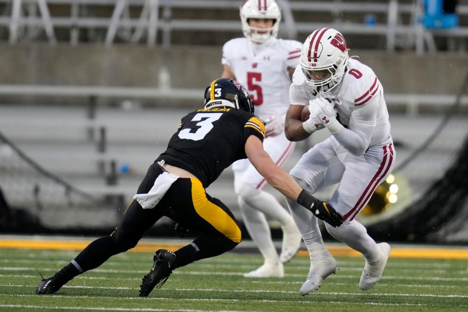 Wisconsin running back Braelon Allen (0) runs from Iowa defensive back Cooper DeJean (3) during the first half of an NCAA college football game, Saturday, Nov. 12, 2022, in Iowa City, Iowa. (AP Photo/Charlie Neibergall) ORG XMIT: IACN110
