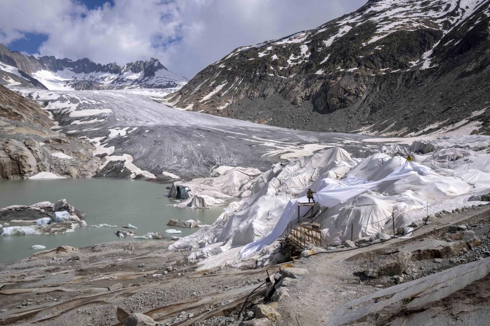 Workers prepare sheets at the Rhone Glacier near Goms, Switzerland, Thursday, June 15, 2023. The sheets are just a small scale solution and Alpine glaciers are still expected to vanish by the end of the century. (AP Photo/Matthias Schrader)