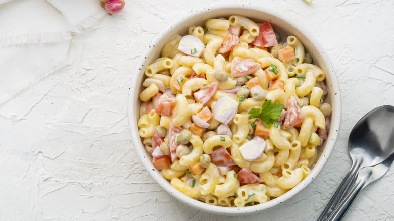 Macaroni salad in speckled dish with wooden spoon