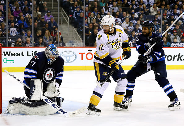 WINNIPEG, MB - NOVEMBER 27: Mike Fisher #12 of the Nashville Predators creates a screen in front of goaltender Connor Hellebuyck #37 of the Winnipeg Jets as the puck flies towards the net during third period action at the MTS Centre on November 27, 2016 in Winnipeg, Manitoba, Canada. (Photo by Darcy Finley/NHLI via Getty Images)