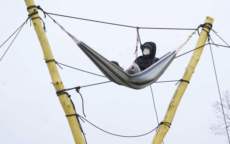 A person sits in a hammock next to the Garzweiler lignite opencast mine at the village Luetzerath near Erkelenz, Germany, Tuesday, Jan. 10, 2023. A court in Germany has rejected a last-ditch attempt by climate activists to stay in an abandoned village which is due to be cleared for the expansion of a coal mine that's become a battleground between the government and environmentalists. (AP Photo/Michael Probst)