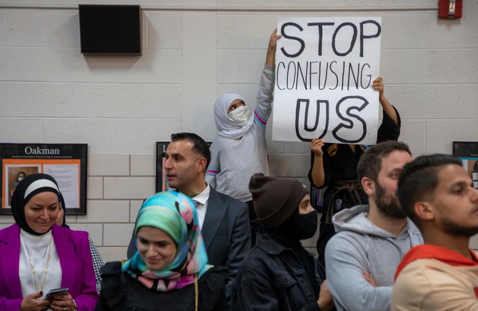 Two young kids hold a sign that reads 'Stop confusing us' during the Dearborn Board of Education meeting in Dearborn on Monday, Oct. 10, 2022.