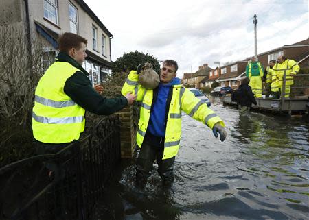 Community volunteers bring sandbags to resident Colin Hall (R) at Egham after the River Thames burst its banks in southeast England February 13, 2014. REUTERS/Luke MacGregor