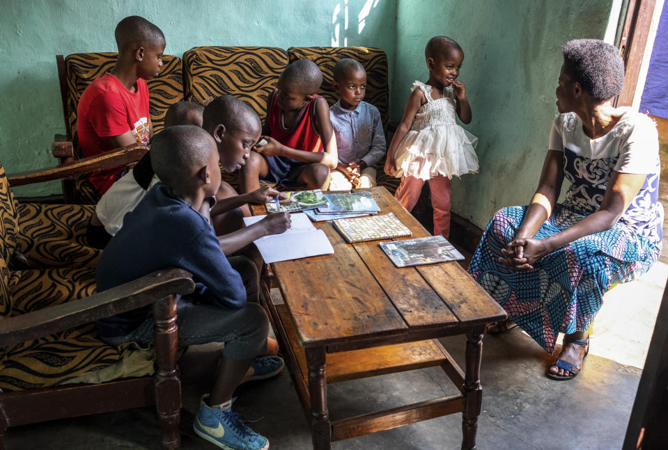 Tresor Ndizihiwe, 12, writes in a book accompanied by his siblings and his mother, Jacqueline Mukantwari, right, at their home in Kigali, Rwanda on Tuesday, April 21, 2020 during the COVID-19 coronavirus lockdown. Mukantwari says her son is a good student -- “so intelligent.” (AP Photo)