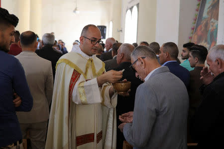 A priest leads the Easter Mass in Mar Gewargis (St George) Chaldean Catholic church, which was damaged by Islamic State militants, in the town of Tel Esqof, Iraq, April 16, 2017. REUTERS/Marko Djurica