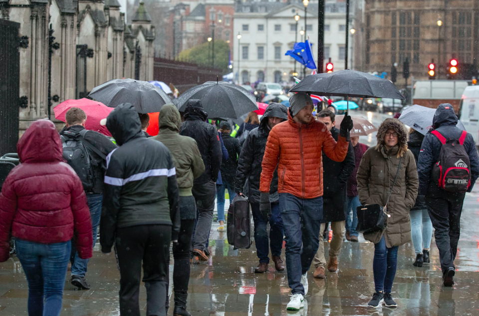 <em>Pedestrians in London walk with umbrellas as heavy rain starts to hit (PA)</em>