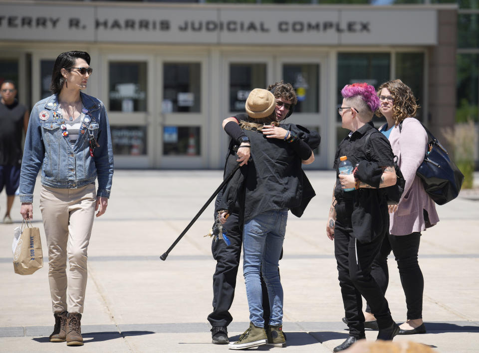 Wyatt Kent, center front, a performer at Club Q during a mass shooting in November 2022, hugs a person outside the courthouse after a hearing for the shooting suspect Monday, June 26, 2023, in Colorado Springs, Colo. The suspect pleaded guilty in the attack that left five people dead and wounded others just before Thanksgiving Day 2022, at the longtime sanctuary for the LGBTQ+ community in this mostly conservative city. (AP Photo/David Zalubowski)