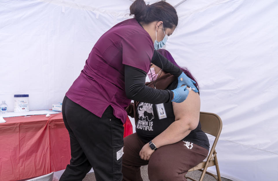 Joana Luna, a temporary medical assistant, left, inoculates Carmen Jimenez, 35, a resident of ZIP code 90001, at the St. John's Well Child and Family Center's COVID-19 vaccination site at the East Los Angeles Civic Center in Los Angeles, Thursday, March 4, 2021. California will begin setting aside 40% of all vaccine doses for the state's most vulnerable neighborhoods in an effort to inoculate people most at risk from the coronavirus more quickly. (AP Photo/Damian Dovarganes)