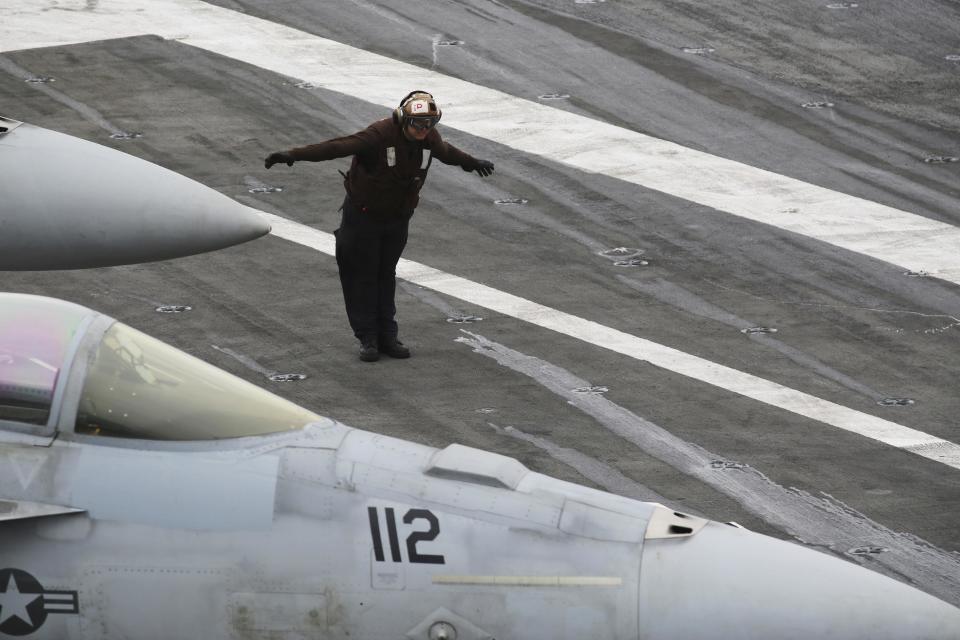 In this Tuesday, March 21, 2017 photograph, a U.S. Navy sailor stands in a driving wind striking the USS George H.W. Bush as it travels through the Strait of Hormuz. The arrival of the nuclear-powered aircraft carrier to the Persian Gulf marks the first such deployment under new U.S. President Donald Trump. (AP Photo/Jon Gambrell)