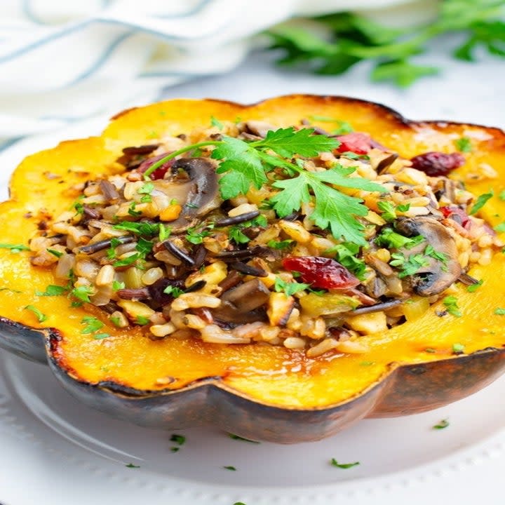 One half of an acorn squash with rice, cranberries, and other filling in it