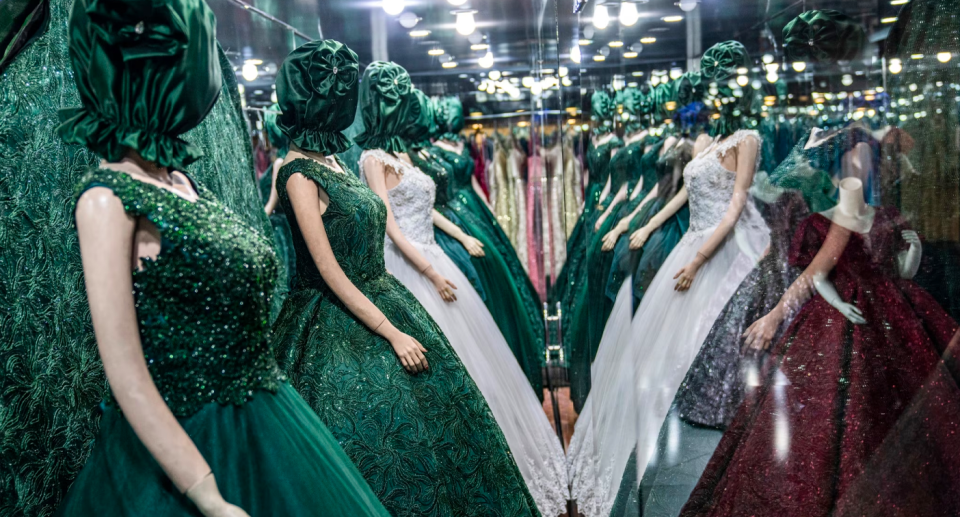 Rows of mannequins with their faces covered in cloth in a shop window. 