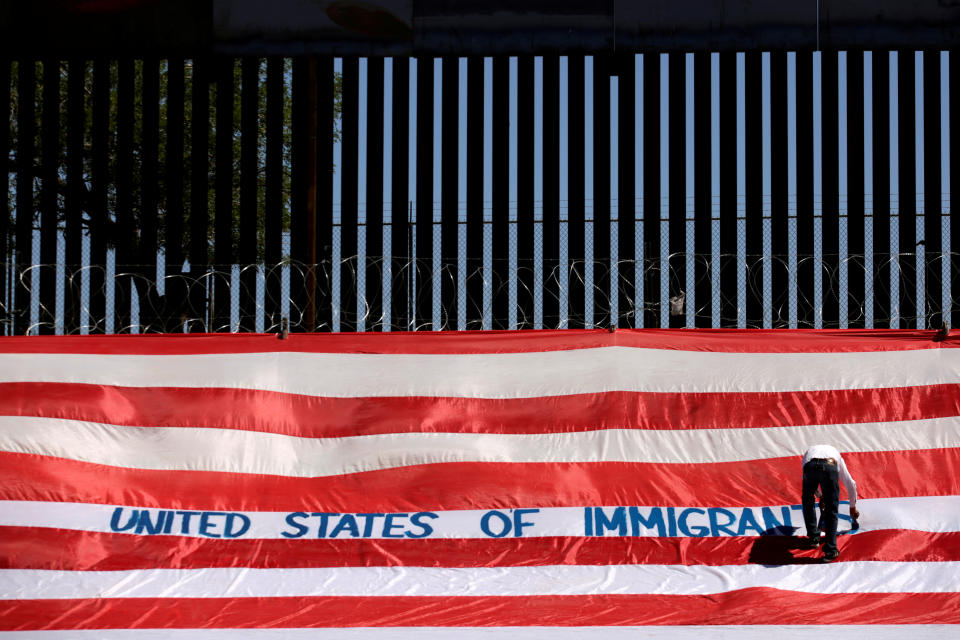 Roberto Marquez, known as Roberz, writes on a large U.S. flag as part of a protest called 'United States of Immigrants', aimed to demand respect for the migrants, near a border wall in El Paso, Texas, as pictured from Ciudad Juarez, Mexico June 6, 2019. REUTERS/Jose Luis Gonzalez     TPX IMAGES OF THE DAY