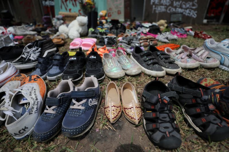 Children's shoes line the base of the defaced statue of Egerton Ryerson in Toronto