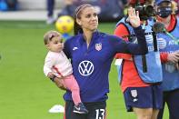 <p>Alex Morgan waves to fans while holding her baby girl Charlie Elena Carrasco after a SheBelieves Cup women's soccer match against Brazil on Sunday in Orlando.</p>