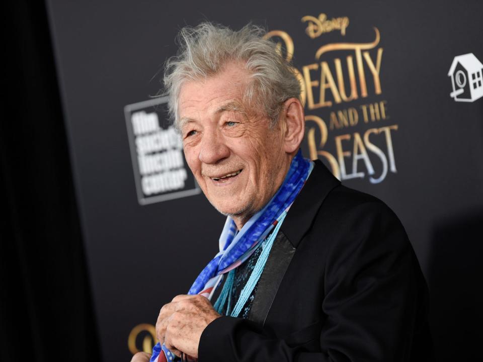 ian mckellen wearing a black suit and blue scarf at the beauty and the beast premiere