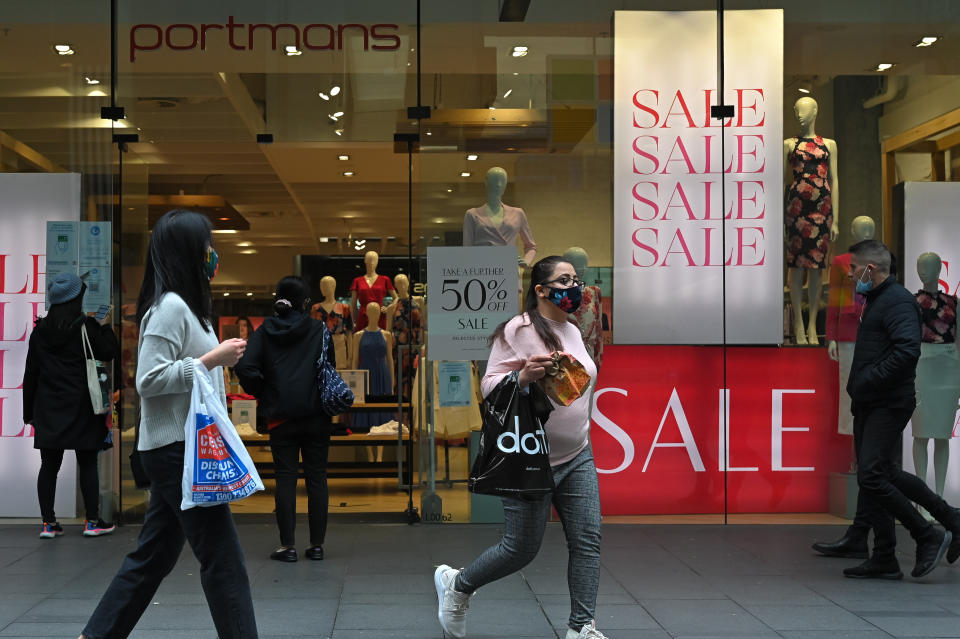 SYDNEY, AUSTRALIA - OCTOBER 12: People carrying shopping bags walk past sales signs in a retail store after stay-at-home orders were lifted across NSW, in Sydney, Australia, Tuesday, October 12, 2021. Having surpassed the 70 per cent double-dose vaccination milestone early, gyms, cafes, restaurants, pools, shops, hairdressers and beauticians will reopen in NSW from Monday. (Photo by Steven Saphore/Anadolu Agency via Getty Images)