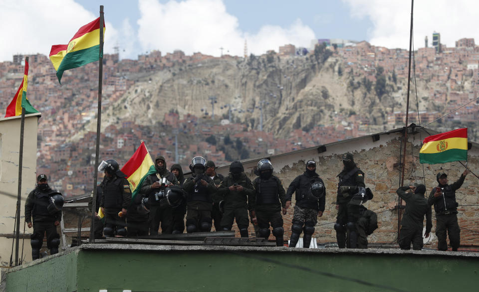 Police against the reelection of President Evo Morales stand on the rooftop of a police station waving national flags just meters away from the presidential palace, in La Paz, Bolivia, Saturday, Nov. 9, 2019. Policemen guarding the exteriors of the presidential palace in La Paz retreated to their barracks on Saturday, while officers in other Bolivian cities have declared mutinies and joined protests against President Evo Morales, who has faced two weeks of unrest over disputed election results. (AP Photo/Juan Karita)