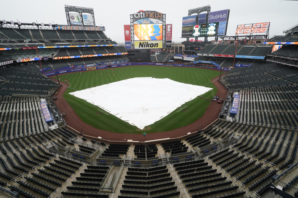 A tarp covers the field after a baseball game between the New York Mets and the Philadelphia Phillies was postponed due to rainy weather, Monday, April 12, 2021, in New York. Monday night's game will be rescheduled as the first game of a single-admission doubleheader, tomorrow, Tuesday, April 13 at 4:10 p.m. (AP Photo/Kathy Willens)