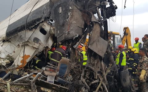 Nepali rescue workers gather around the debris of an airplane that crashed near the international airport in Kathmandu  - Credit: PRAKASH MATHEMA/AFP/Getty Images