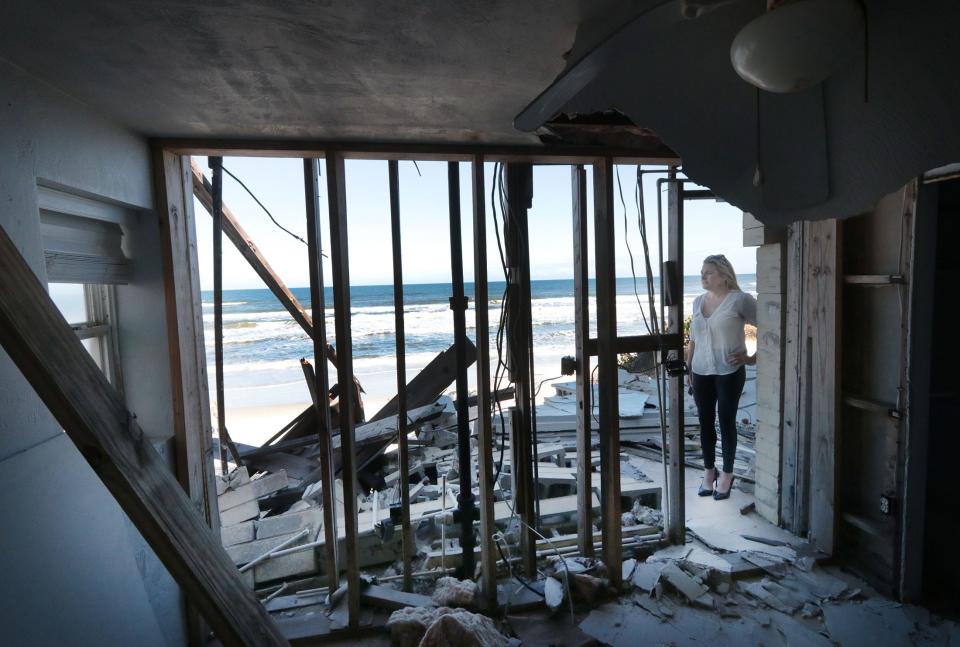 Property manager Krista Goodrich looks over the heavily damaged home at 4109 South Atlantic Ave. on Nov. 7, 2023, as cleanup work in Wilbur-by-the-Sea area continues after Tropical Storm Nicole hit Volusia County.