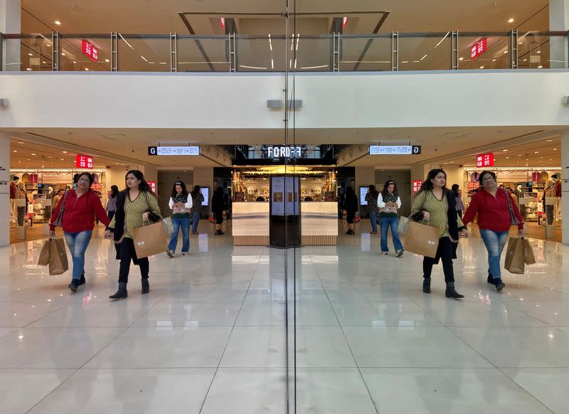 Shoppers are reflected in mirror inside a shopping mall in New Delhi