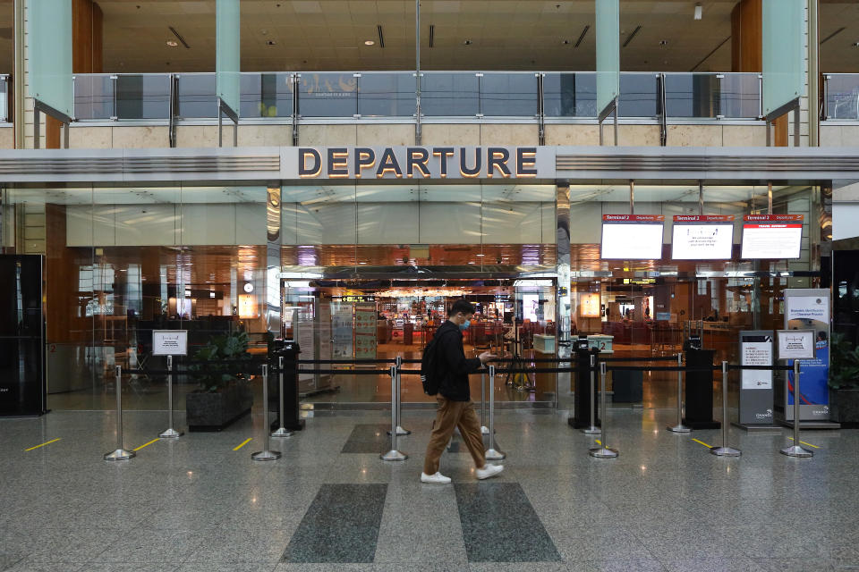 A man wearing a protective mask walks past a closed departure gate at Changi Airport Terminal 2 in Singapore. (Photo by Suhaimi Abdullah/Getty Images)