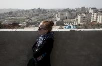 In this photo taken Wednesday, April 16, 2014, a female member of an Israeli and foreigner's group tour that is organized by IPCRI, an Israeli Palestinian group promoting co-existence, listens to a Palestinian guide while visiting the outskirts of the West Bank city of Ramallah. This bustling center of Palestinian life is just a 20-minute drive from Jerusalem, but for Israelis it might as well be on the other side of the world. (AP Photo/Nasser Nasser)