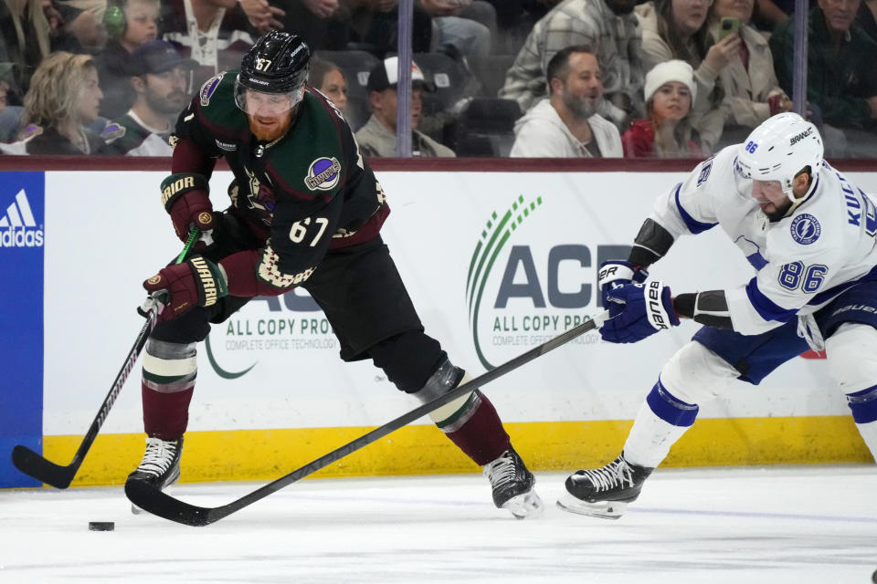 Arizona Coyotes left wing Lawson Crouse (67) battles with Tampa Bay Lightning right wing Nikita Kucherov (86) for the puck during the first period of an NHL hockey game Tuesday, Nov. 28, 2023, in Tempe, Ariz. (AP Photo/Ross D. Franklin)