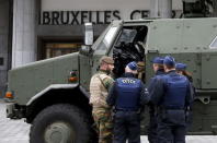 A Belgian soldier and police officers stand next to a military armoured vehicle parked at the entrance of Brussels central train station, November 22, 2015, after security was tightened in Belgium following the fatal attacks in Paris. REUTERS/Francois Lenoir
