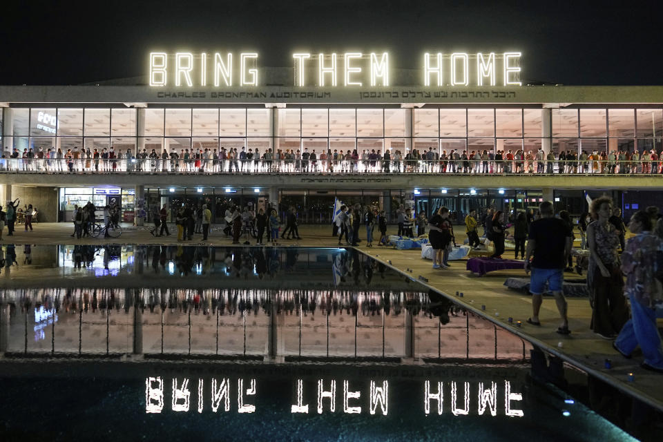 People stand under a sign saying "bring them home" during a rally calling for the return of the hostages kidnapped during the Oct. 7 Hamas cross-border attack in Israel, in Tel Aviv, Israel, Saturday, Nov. 11, 2023. (AP Photo/Ohad Zwigenberg)